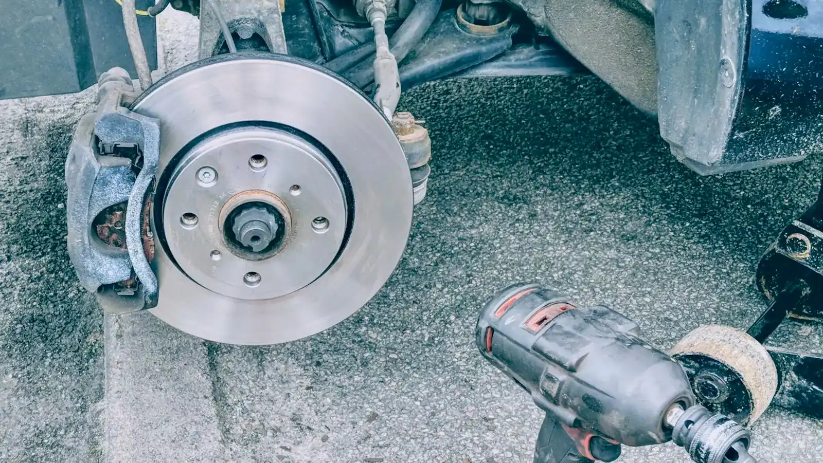 A technician replacing a car's brake pads on a driveway