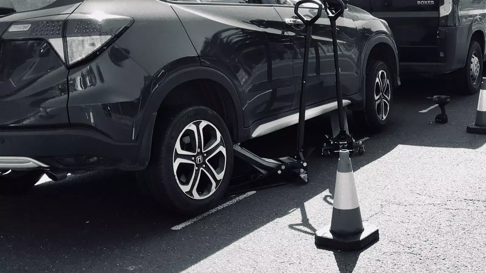 Car raised on a trolley jack with safety cones during a mobile tyre fitting